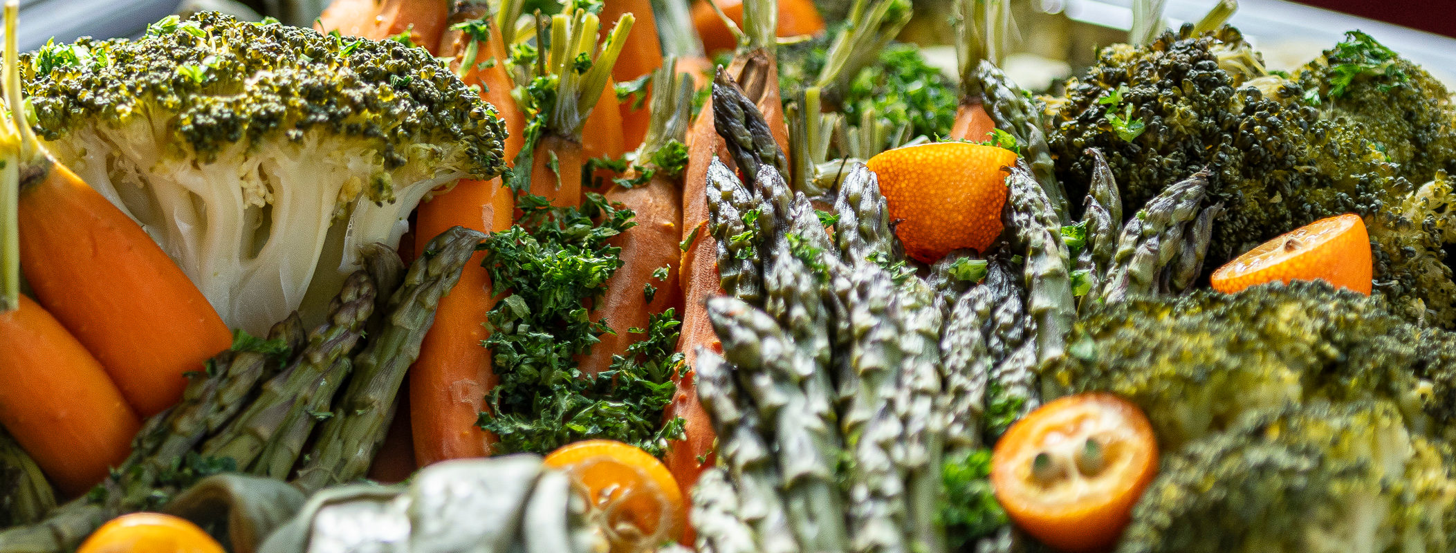 Gemüseplatte mit Brokkoli, grünem Spargel und Kumquats