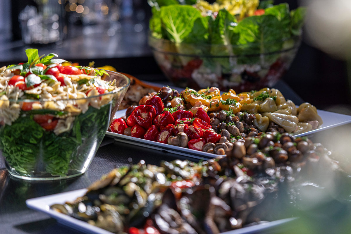Buffet mit Nudelsalat, gefüllten Peperoni und Antipasti